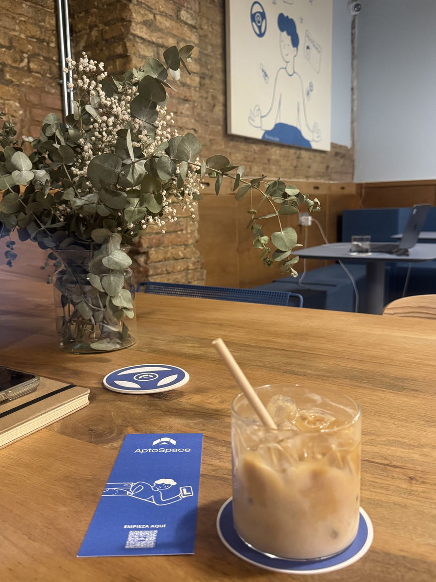 Café helado en la sala de AptoSpace, con las ilustraciones de marca sobre la pared de ladrillo