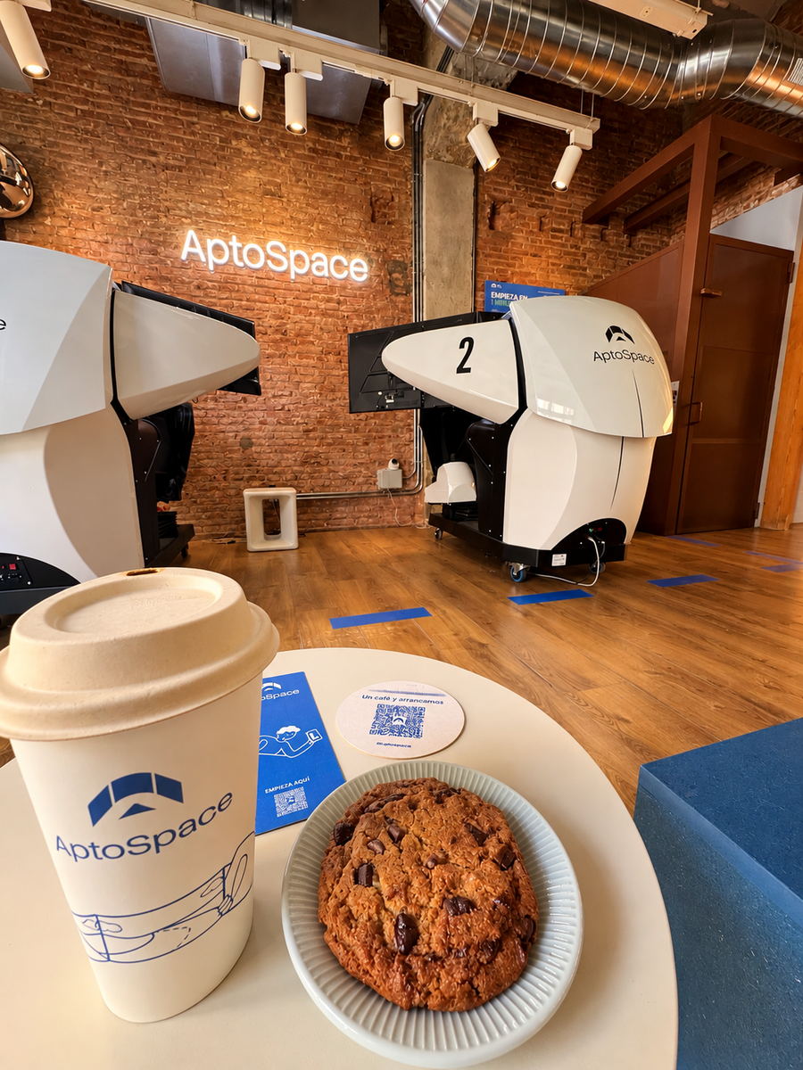 Café para llevar y galleta delante de los dos simuladores de AptoSpace